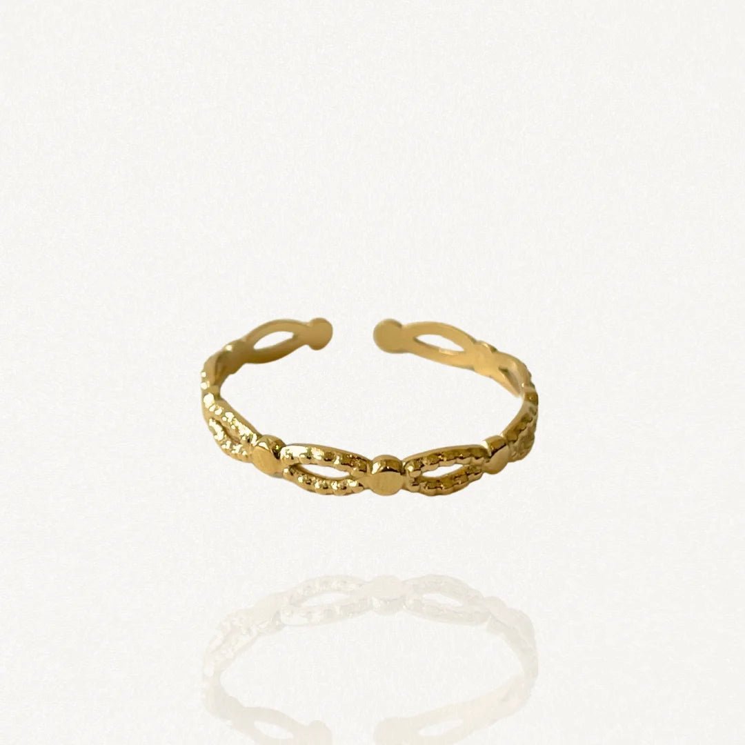 Bague fine ouverte en acier inoxydable doré avec motif maillons ajourés style dentelle sur fond blanc.