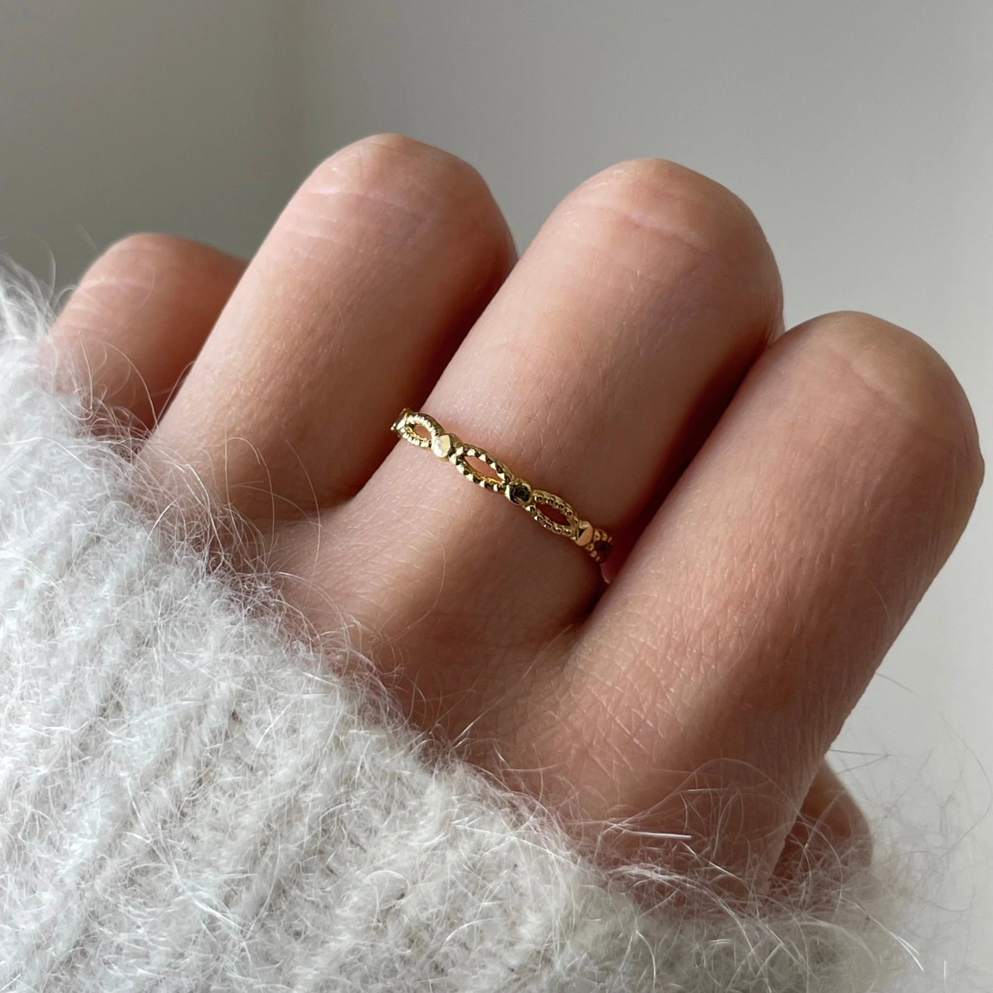 Gros plan bague fine Louisa à motifs maillons portée au doigt, bijou minimaliste et discret.