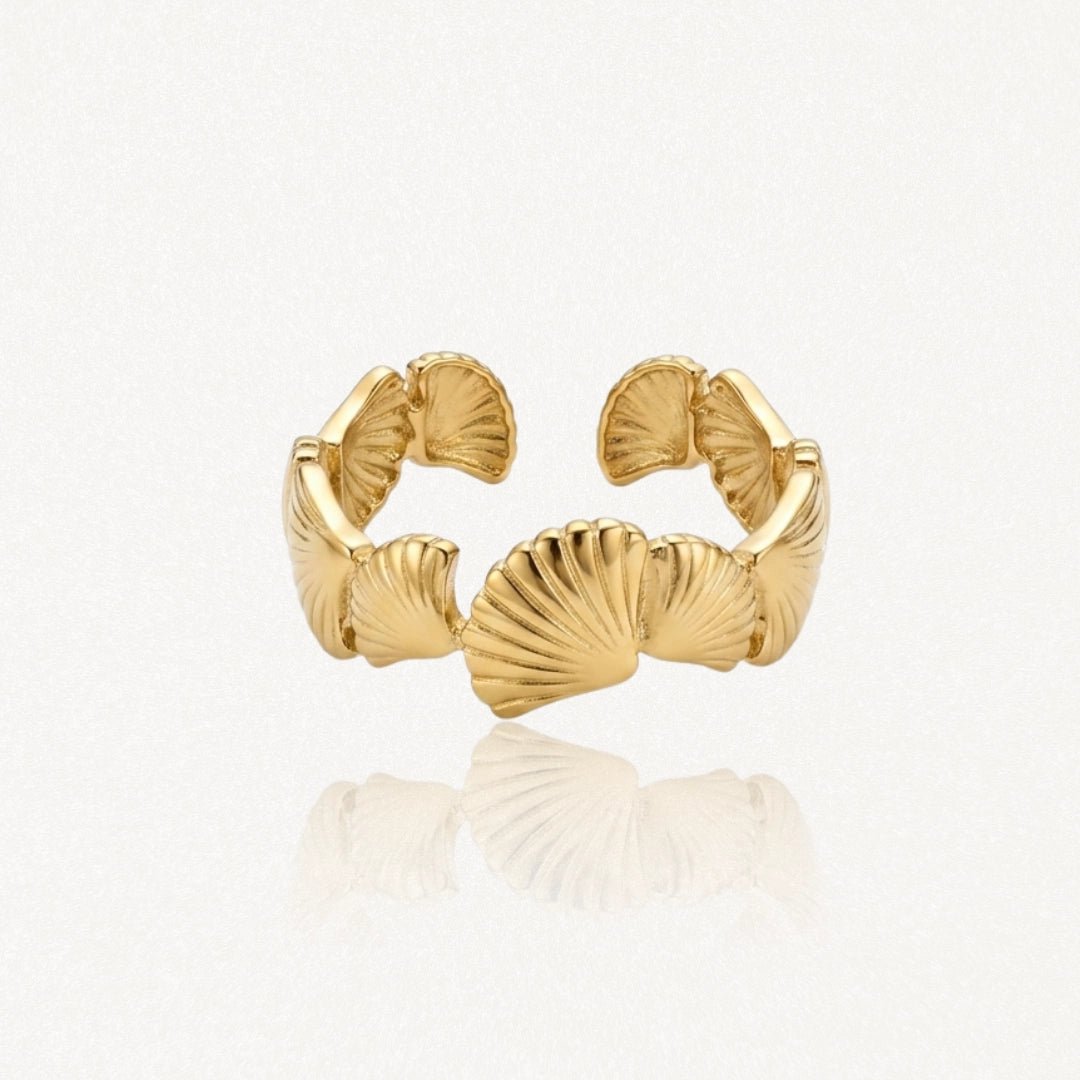 Bague ouverte ajustable en acier inoxydable doré, motif coquillages stylisés avec nervures, finition brillante.