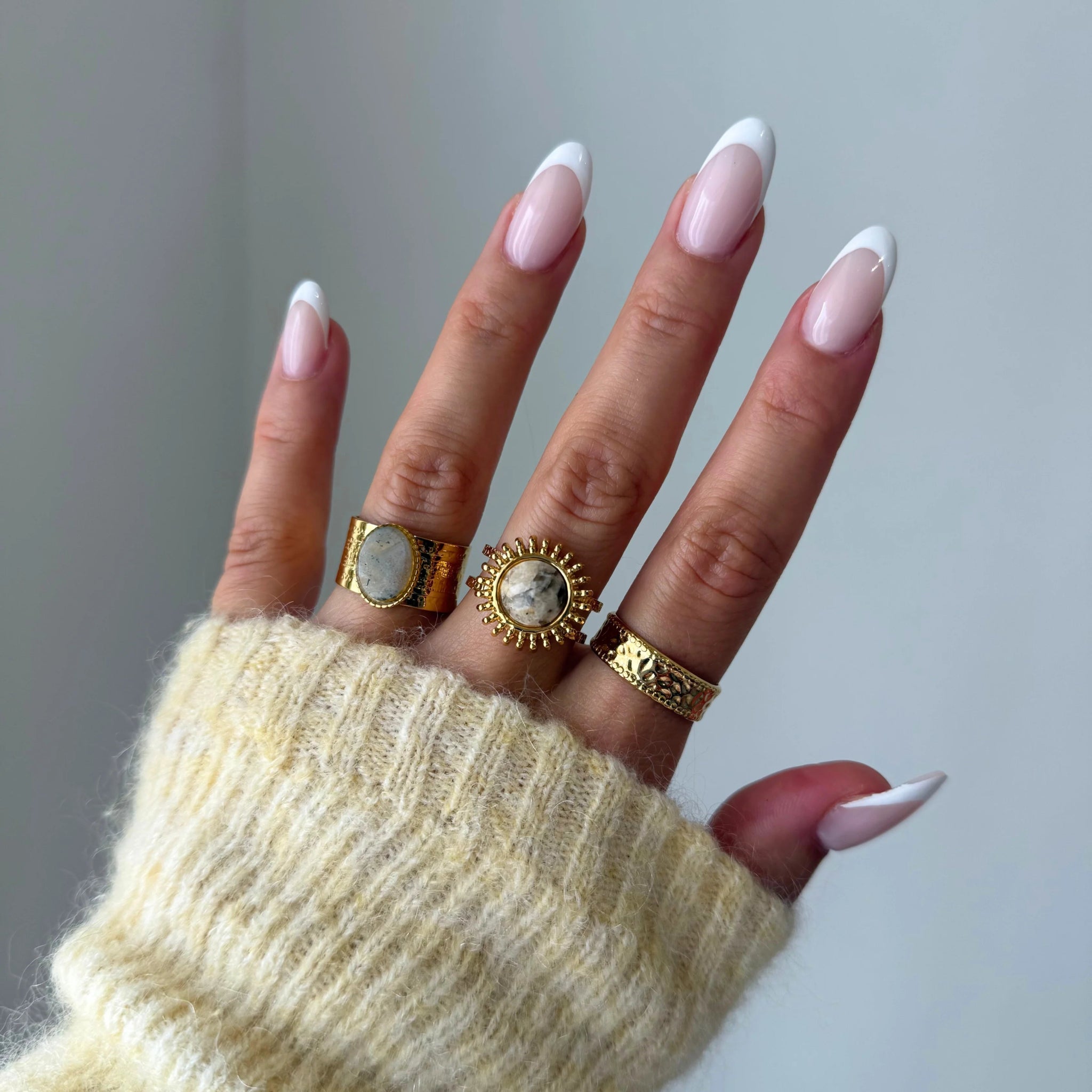 Bague large Luciana portée en accumulation (stacking) avec d'autres bagues dorées texturées et pierres naturelles.