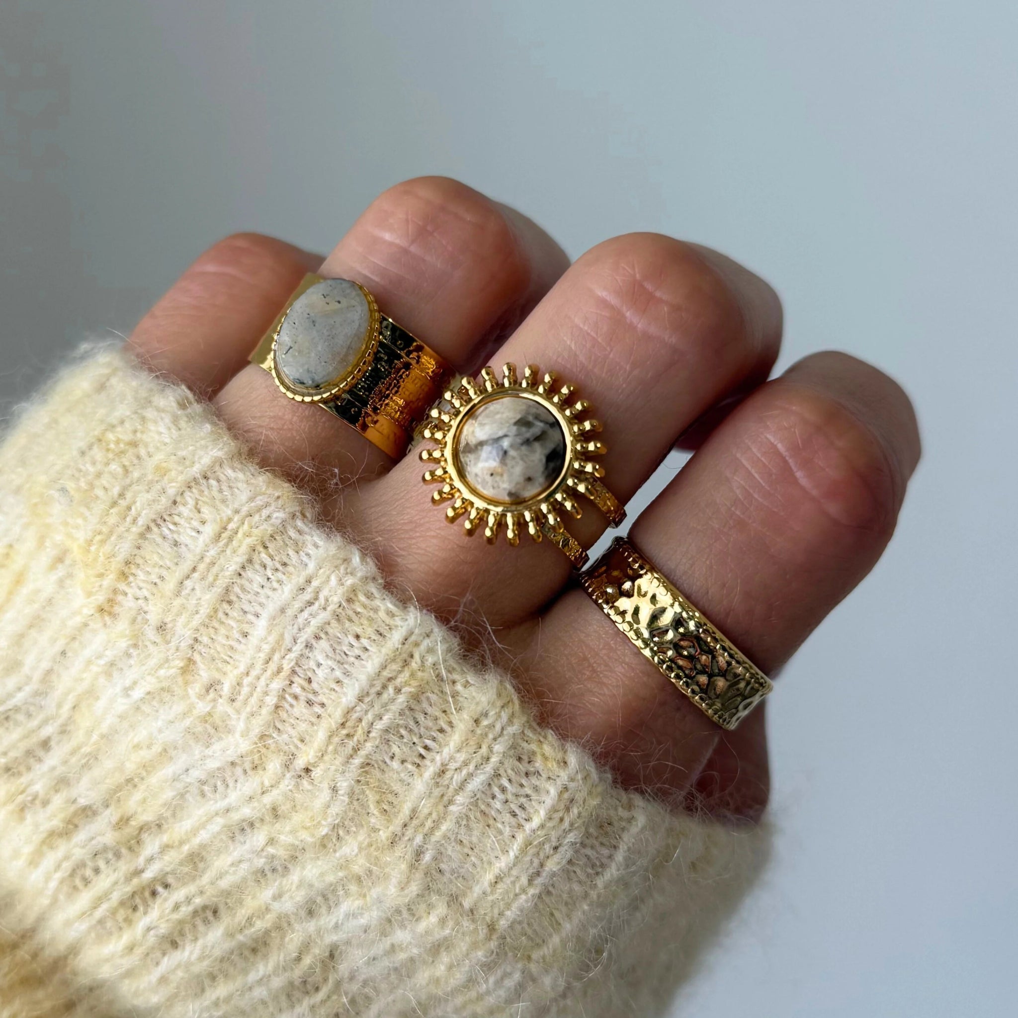 Bague large Luciana portée en accumulation (stacking) avec d'autres bagues dorées texturées et pierres naturelles.