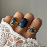 Bague Lucie portée en accumulation (stacking) avec d'autres bagues dorées serties de pierres bleues naturelles.