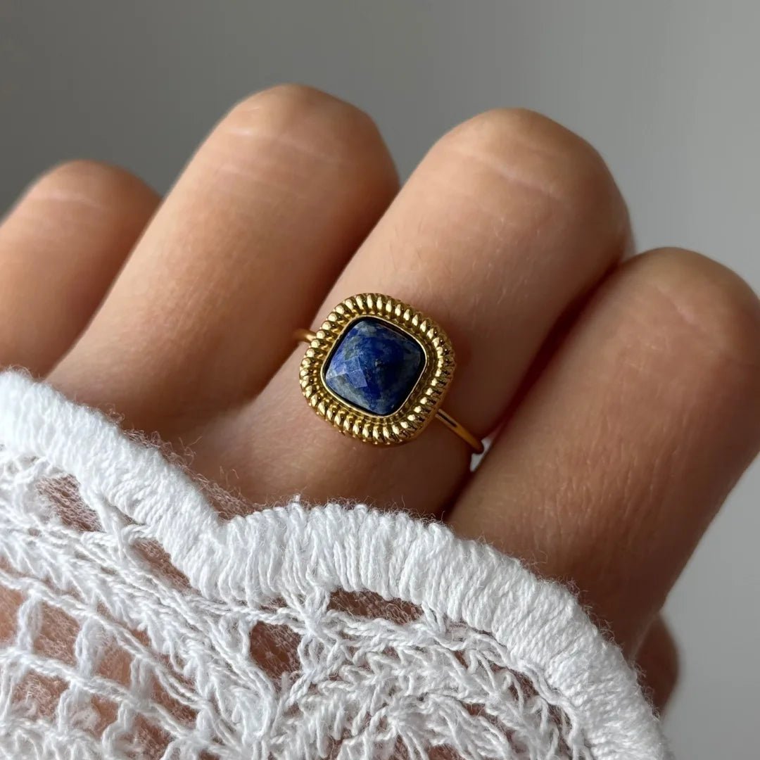 Gros plan bague Lucie style vintage avec pierre bleue marine forme coussin portée au doigt, accessoire chic et intemporel.
