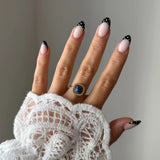 Gros plan bague Lucie style vintage avec pierre bleue marine forme coussin portée au doigt, accessoire chic et intemporel.