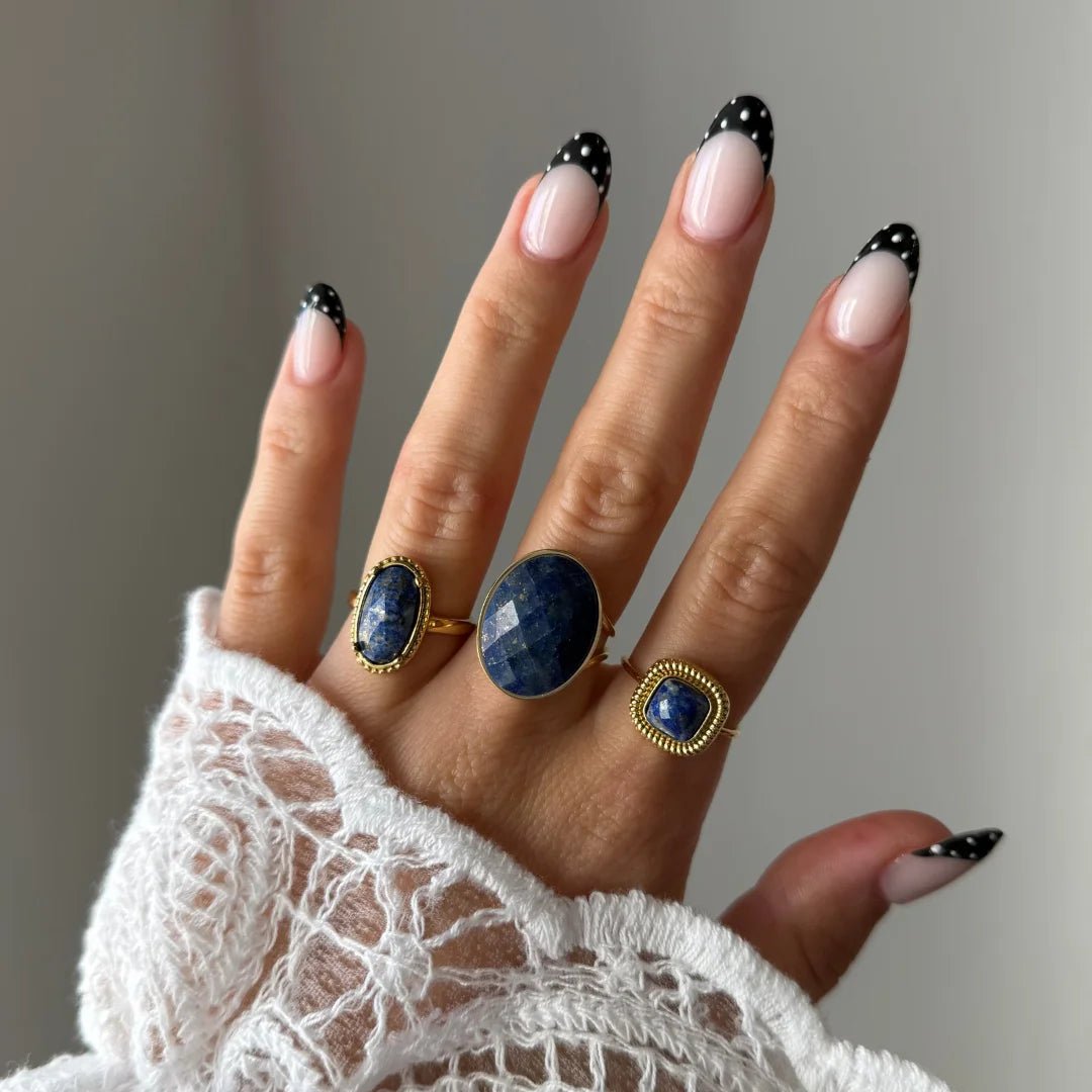 Bague Lucie portée en accumulation (stacking) avec d'autres bagues dorées serties de pierres bleues naturelles.