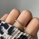 Gros plan bague Lucrecia effet croisé et texturé portée au doigt, bijou minimaliste et lumineux.