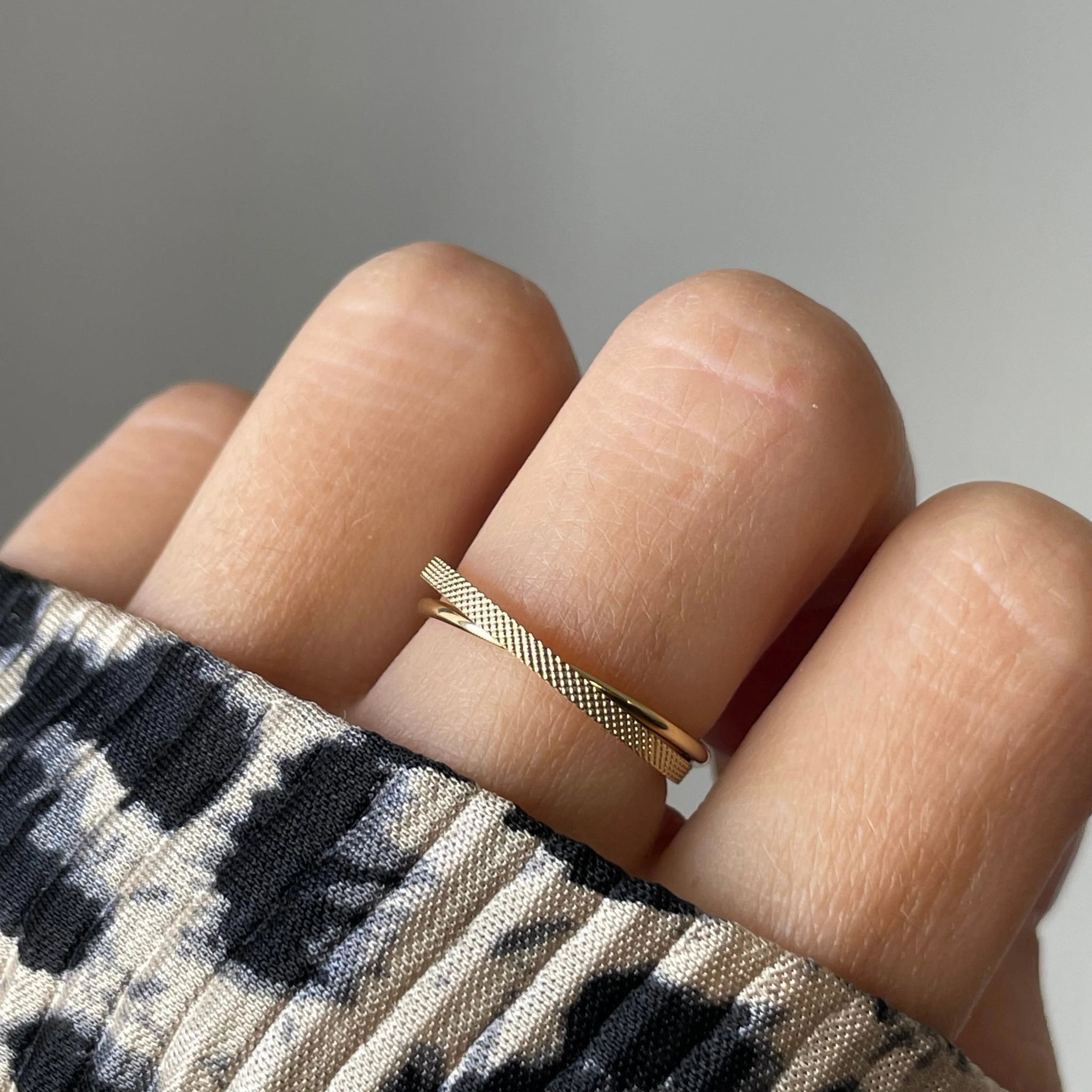 Gros plan bague Lucrecia effet croisé et texturé portée au doigt, bijou minimaliste et lumineux.