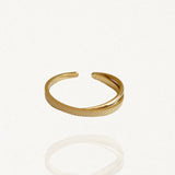 Bague fine ouverte en acier inoxydable doré avec motif croisé : un anneau lisse et un anneau texturé scintillant sur fond blanc.