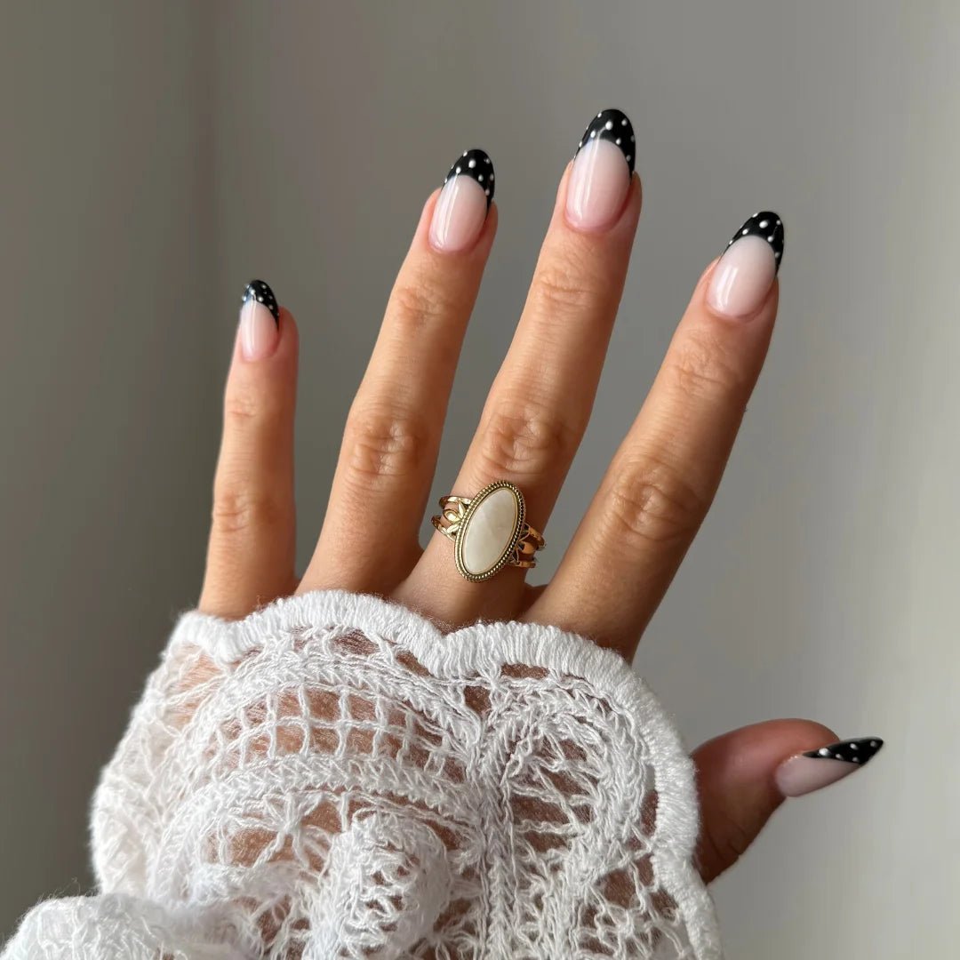 Bague Manon style vintage avec pierre blanche portée sur une main avec manche en dentelle, look bohème.