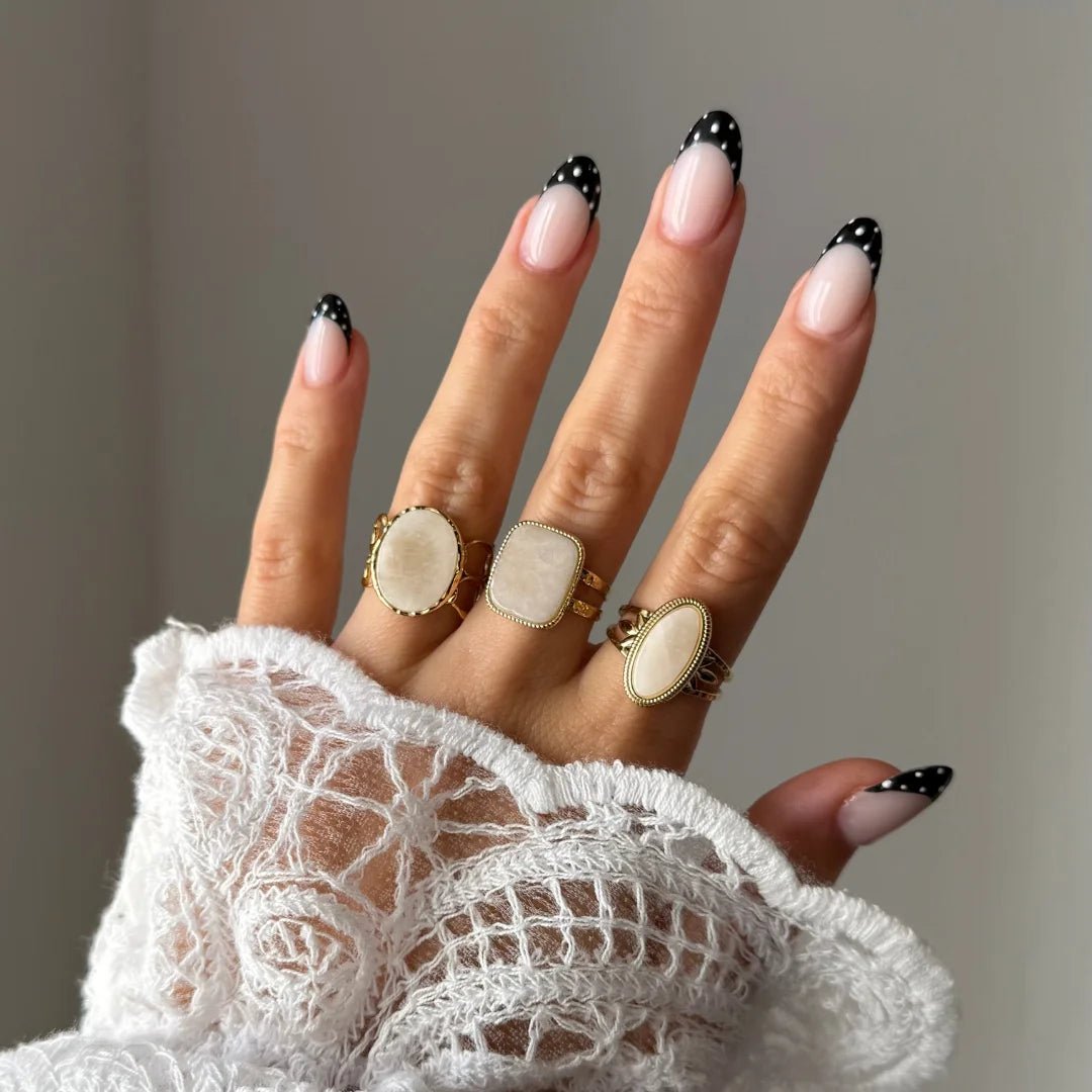 Bague Manon portée en accumulation avec d'autres bagues dorées à pierres naturelles blanches et beiges.