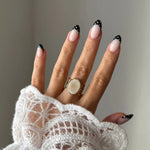 Bague Margot style vintage bohème avec pierre ronde blanche portée sur une main avec manche en dentelle.