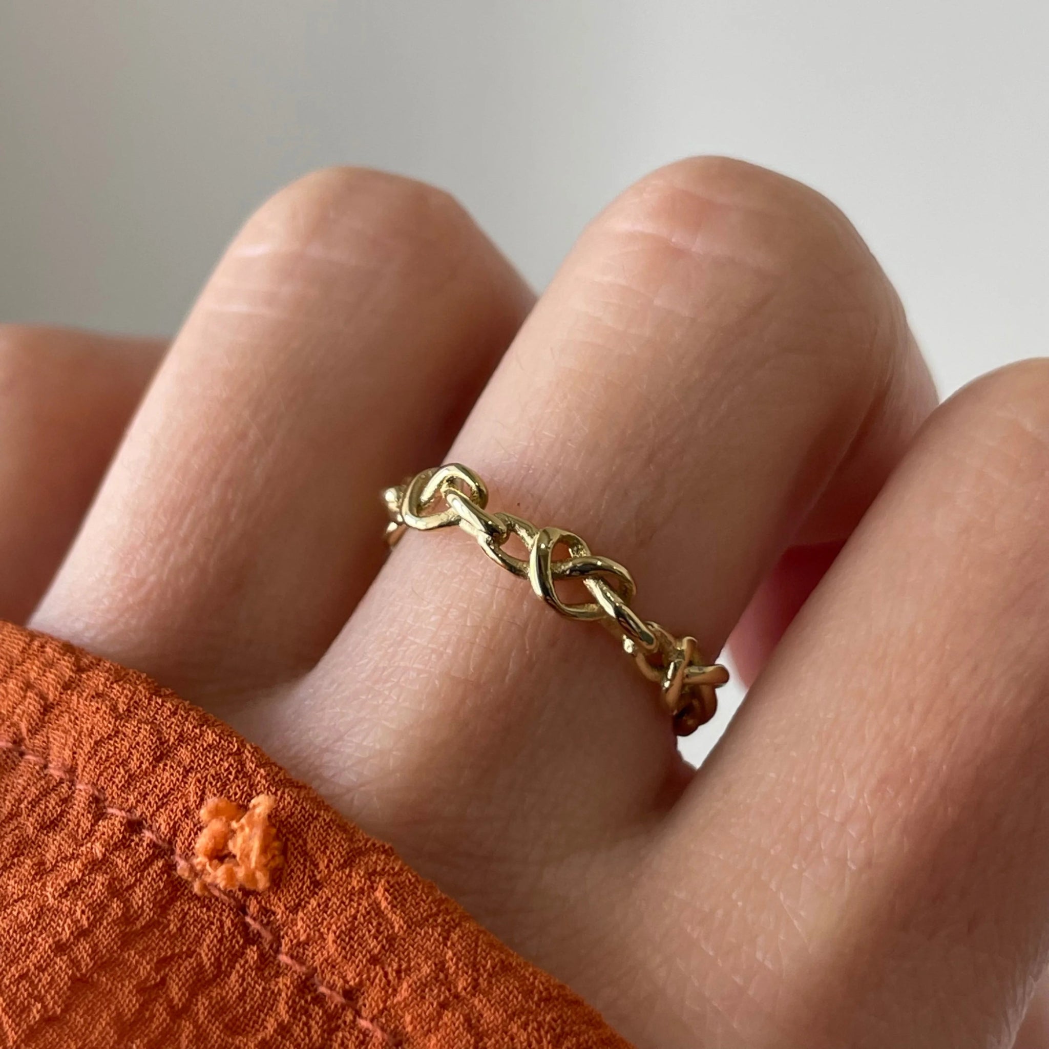 Gros plan bague Marina à maillons forme nœuds portée au doigt, bijou fin et délicat.