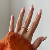 Gros plan bague Marina à maillons forme nœuds portée au doigt, bijou fin et délicat.