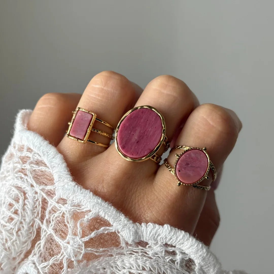 Bague Mathilde portée en accumulation (stacking) avec d'autres bagues larges à pierres roses pour un camaïeu romantique.