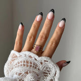 Bague Mathilde style vintage bohème avec pierre rose rectangulaire portée au doigt avec manche en dentelle.