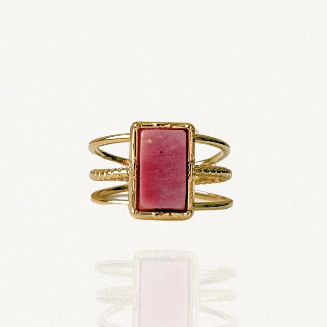 Bague large multi-rangs en acier inoxydable doré ornée d'une pierre naturelle rectangulaire rose vieux rose (style rhodonite) sur fond blanc.