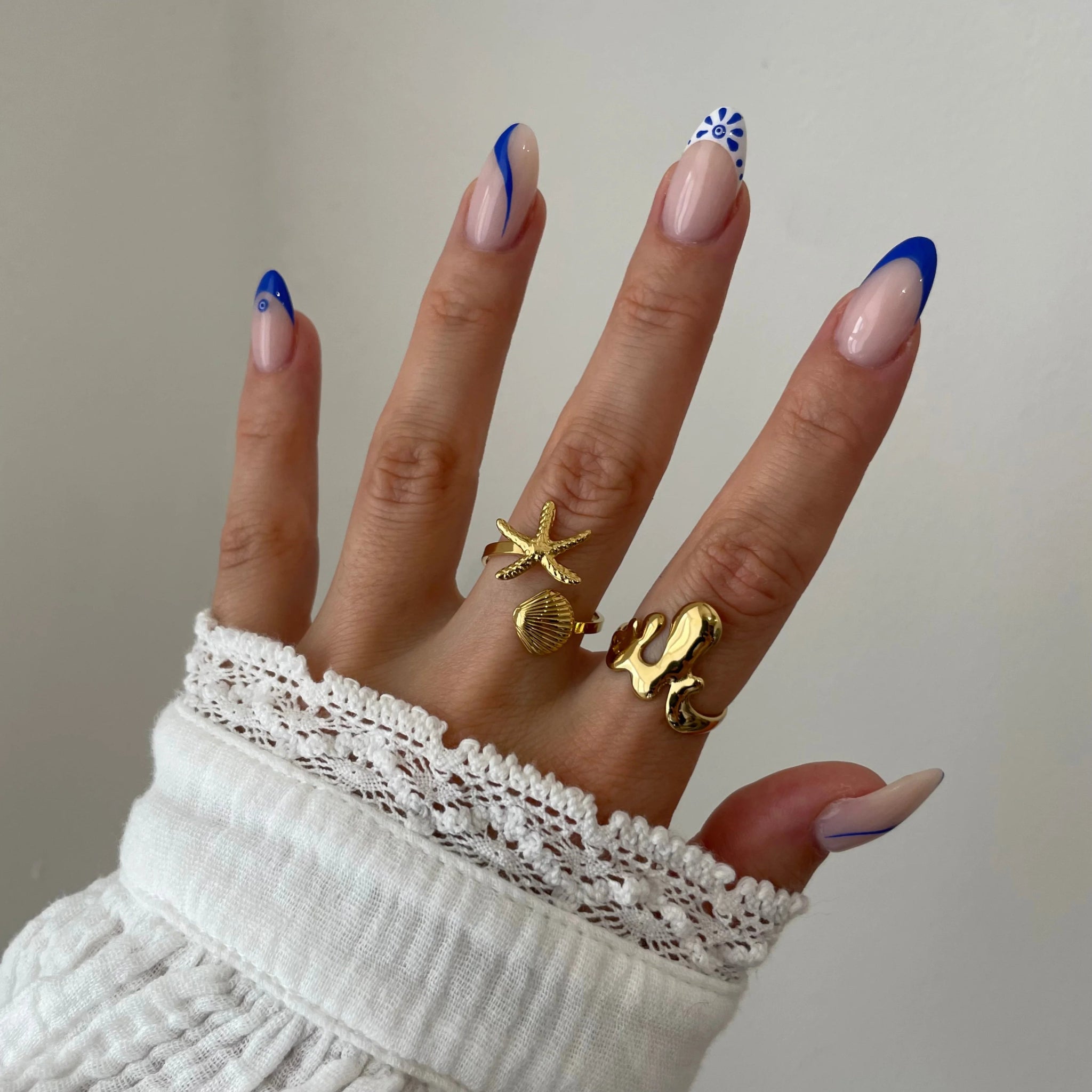 Bague organique Mattia portée en accumulation (stacking) avec une bague étoile de mer et d'autres bijoux dorés.