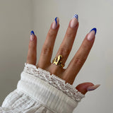 Gros plan bague Mattia style métal fondu ou gouttes d'eau fluides portée au doigt, design artistique et moderne.