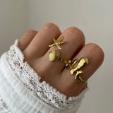 Bague organique Mattia portée en accumulation (stacking) avec une bague étoile de mer et d'autres bijoux dorés.