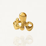 Bague large au design abstrait et organique forme gouttes de métal liquide en acier inoxydable doré sur fond blanc.