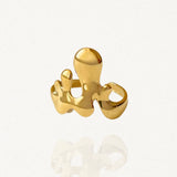 Bague large au design abstrait et organique forme gouttes de métal liquide en acier inoxydable doré sur fond blanc.