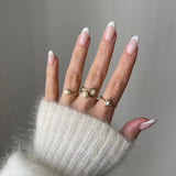 Bague fine Melania portée en accumulation (stacking) avec d'autres bagues dorées et perles sur une main manucurée.