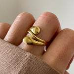 Gros plan bague Mina forme gouttes d'eau fluides portée au doigt, design moderne.