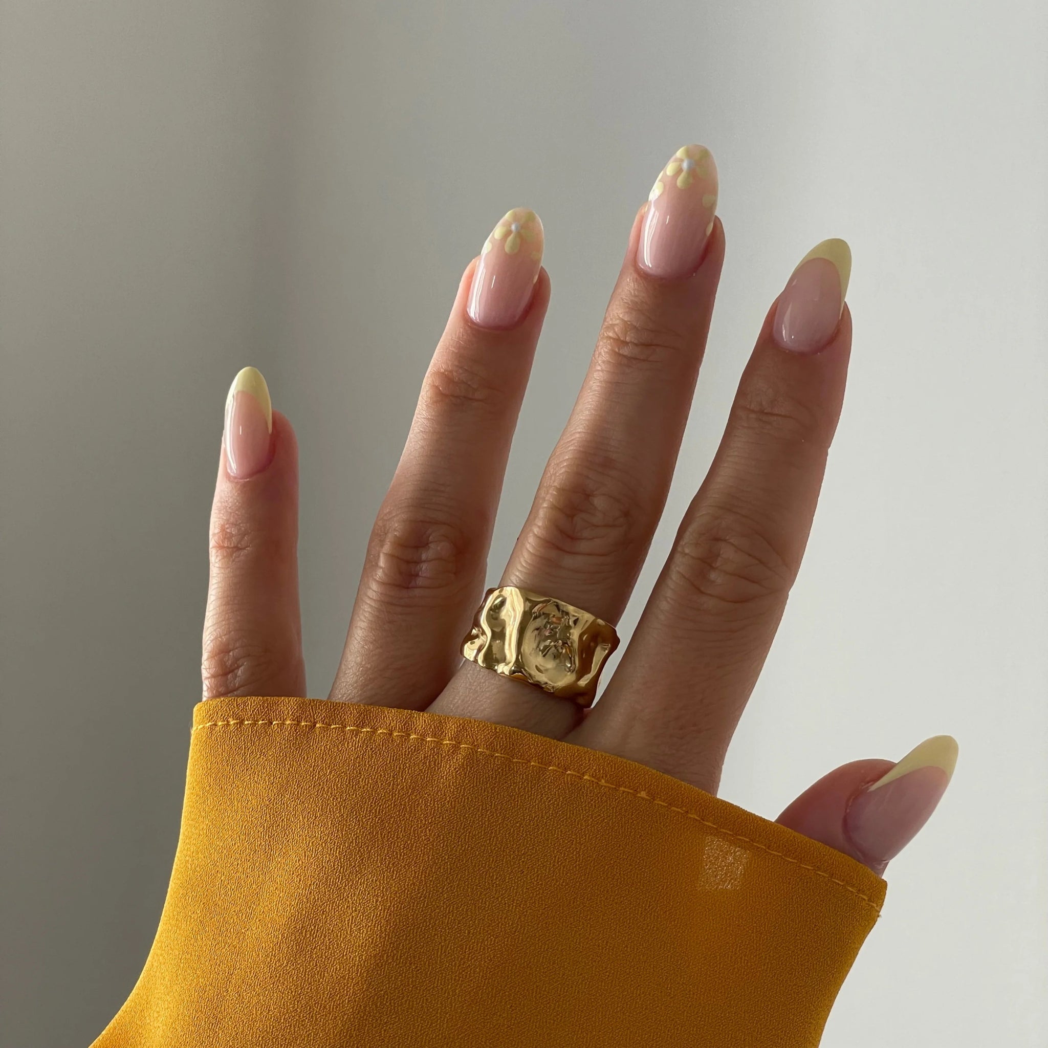 Bague statement large et dorée portée au doigt, accessoire mode tendance.