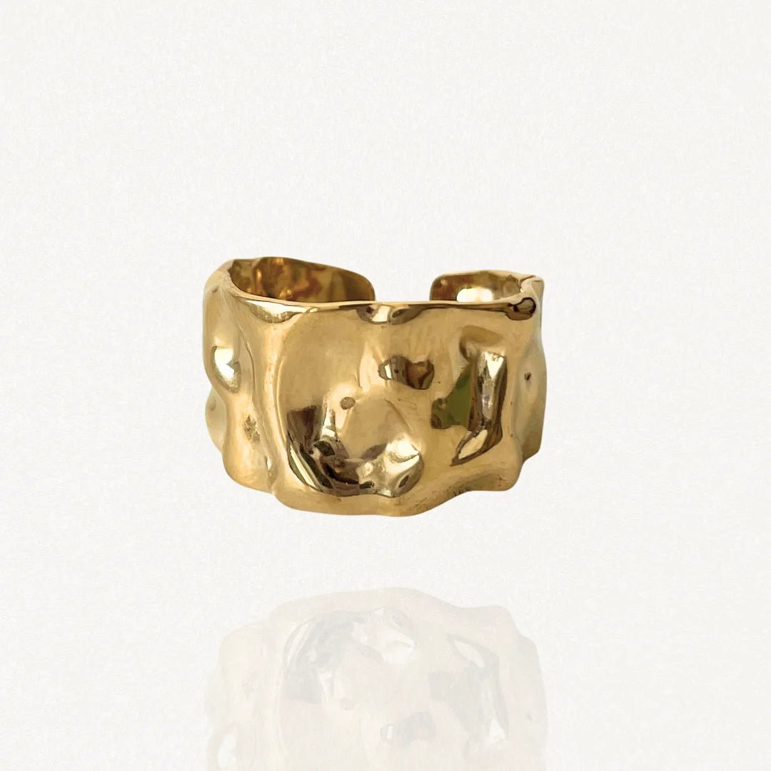 Bague large ajustable en acier inoxydable doré avec effet martelé et texturé sur fond blanc.