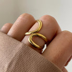 Gros plan bague Monica au design filaire ondulé portée au doigt, style minimaliste chic.