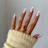 Bague Mylena dorée avec pierre rouge portée au doigt, accessoire chic avec pull maille.