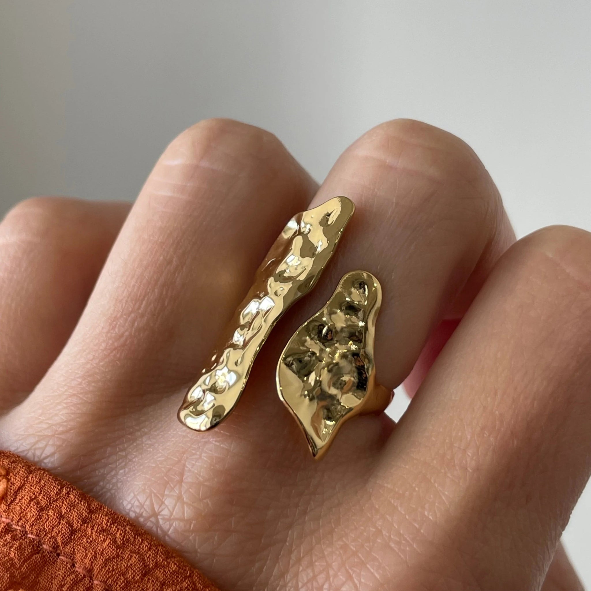 Gros plan bague Nicola au design organique et allongé qui habille le doigt, finition texturée dorée.