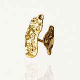 Bague statement allongée en acier inoxydable doré avec deux plaques irrégulières effet martelé sur fond blanc.