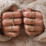 Bague fine Ninon portée en accumulation (stacking) avec d'autres bagues dorées lisses et texturées sur les deux mains.