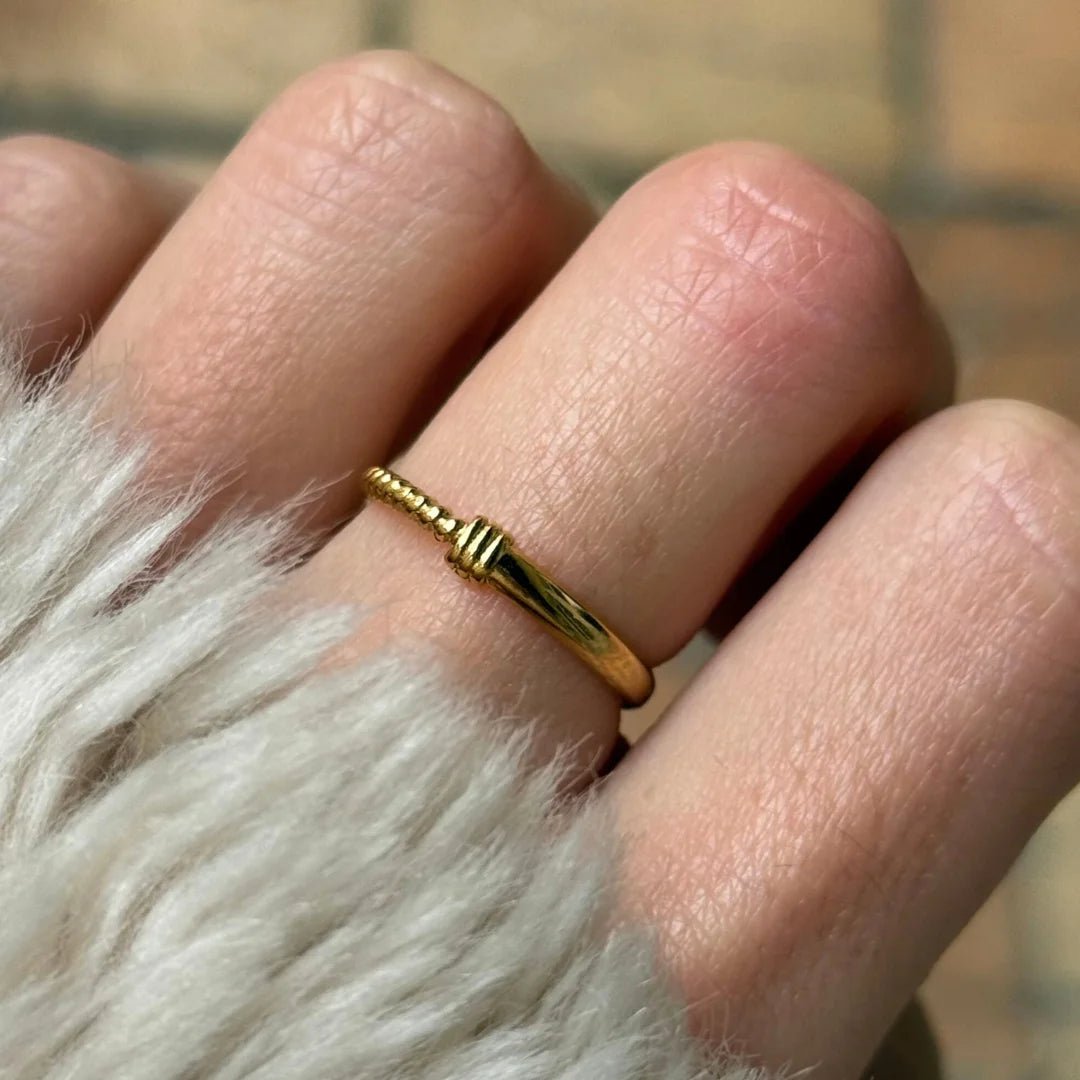 Gros plan bague fine Ninon à relief strié minimaliste portée au doigt.
