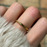 Gros plan bague fine Ninon à relief strié minimaliste portée au doigt.