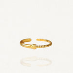 Bague fine ouverte en acier inoxydable doré avec détail texturé effet strié ou bobine sur fond blanc.