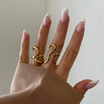 Bague Paola style moderne et artistique portée sur la main, design filaire doré original.