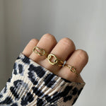 Bague nœud torsadé Roberta portée en accumulation (stacking) avec d'autres bagues fines dorées.