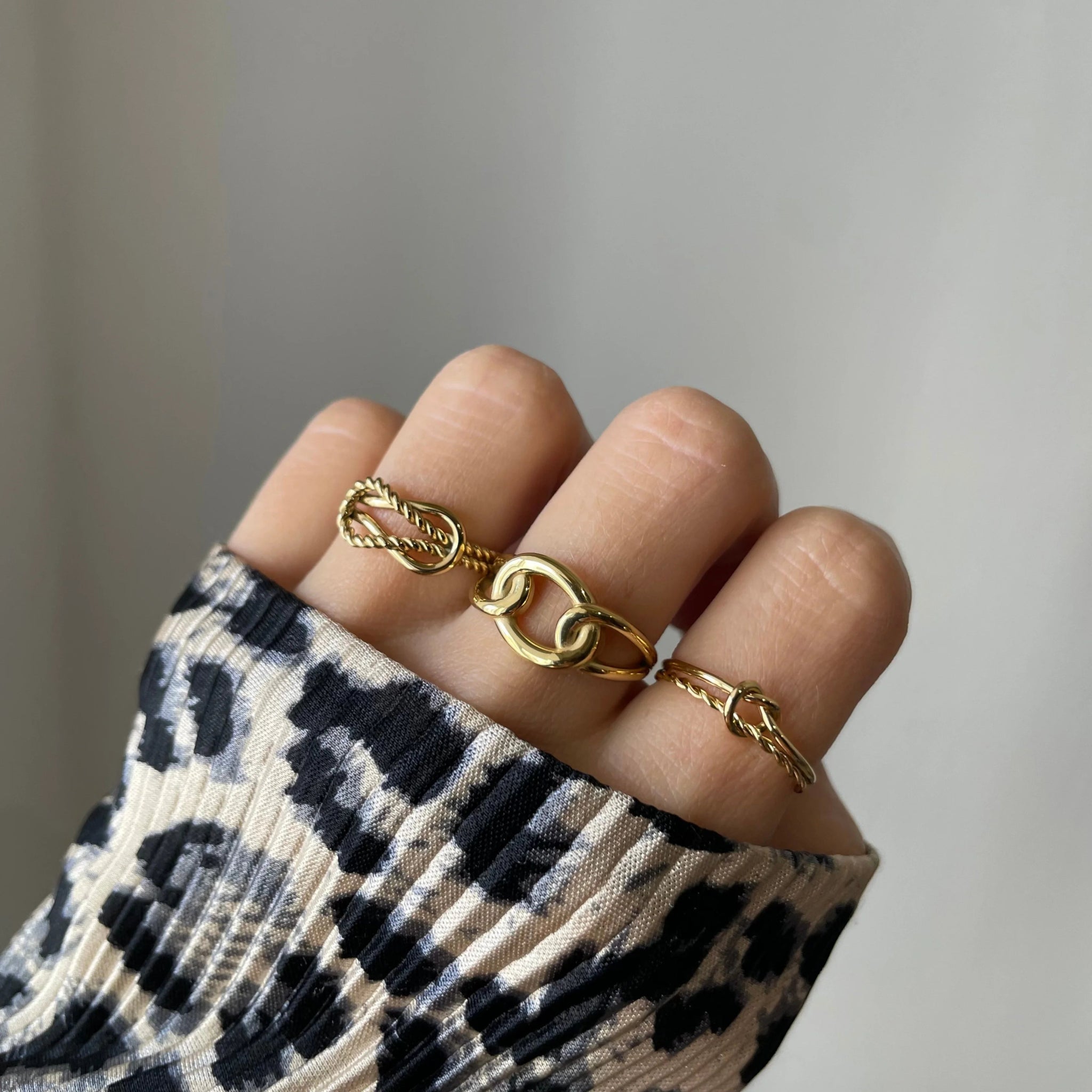 Bague nœud torsadé Roberta portée en accumulation (stacking) avec d'autres bagues fines dorées.