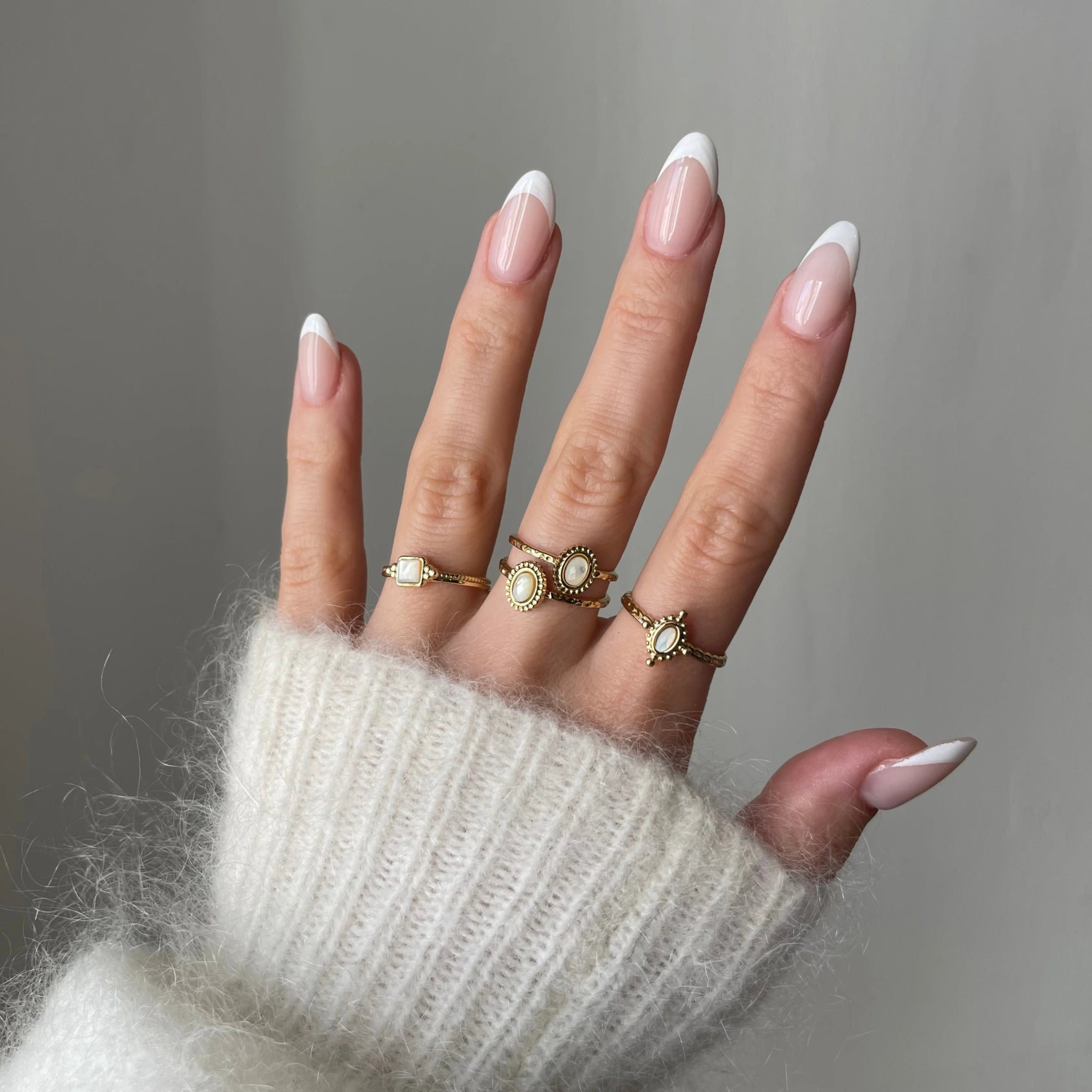 Bague Rosaria portée en accumulation (stacking) avec d'autres bagues fines dorées et pierres blanches sur une main.