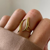 Gros plan bague Samanta au design organique et fluide portée au doigt, style moderne et graphique.