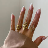 Bague graphique Samanta portée en accumulation (stacking) avec d'autres bagues dorées sur une main manucurée.
