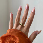 Gros plan bague Sandra motif couronne de fleurs portée au doigt, style romantique et printanier.