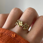 Gros plan bague Sandra motif couronne de fleurs portée au doigt, style romantique et printanier.