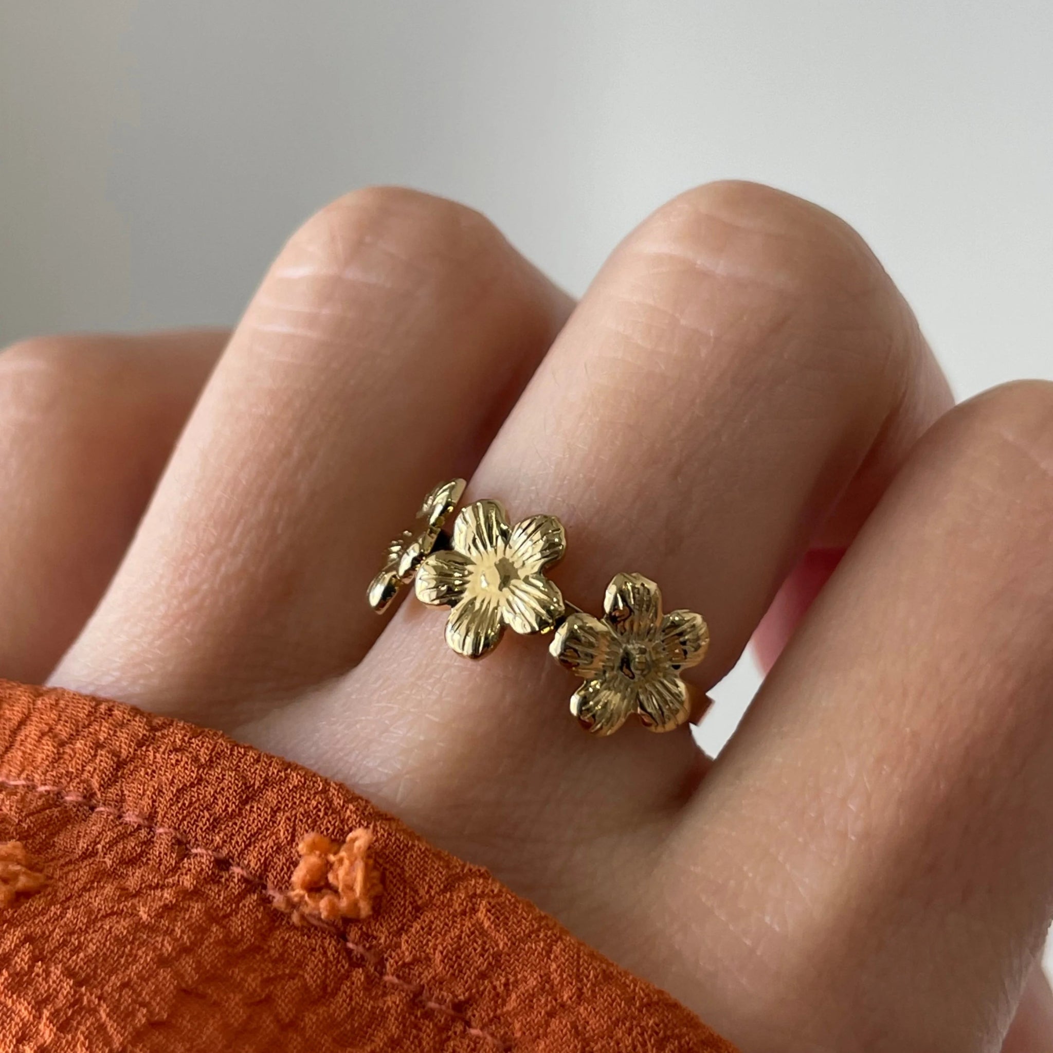 Gros plan bague Sandra motif couronne de fleurs portée au doigt, style romantique et printanier.