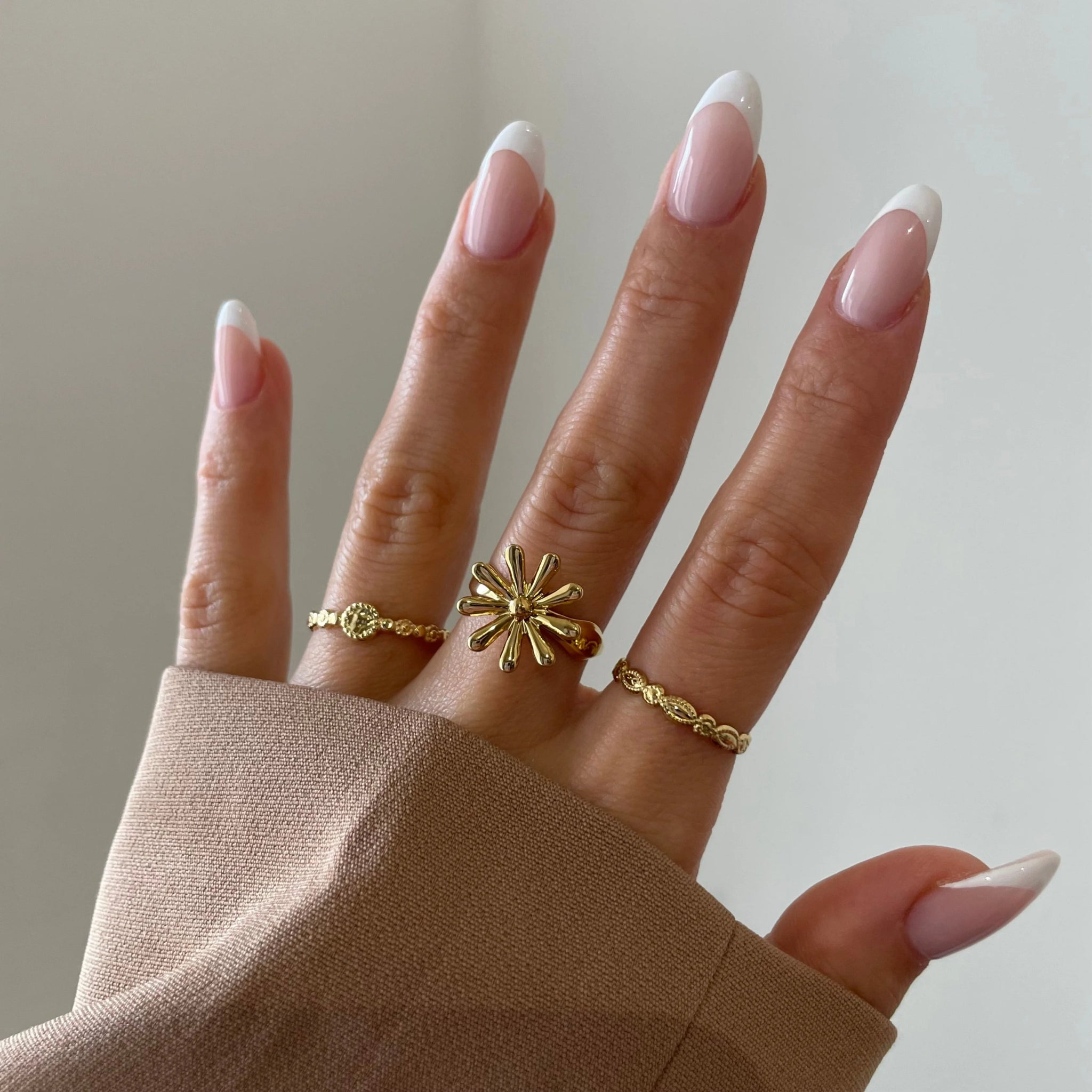 Bague Savanna portée en accumulation (stacking) avec une bague fleur statement sur une main manucurée.