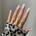 Bague large Svetlana portée en accumulation (stacking) avec d'autres bagues géométriques dorées.