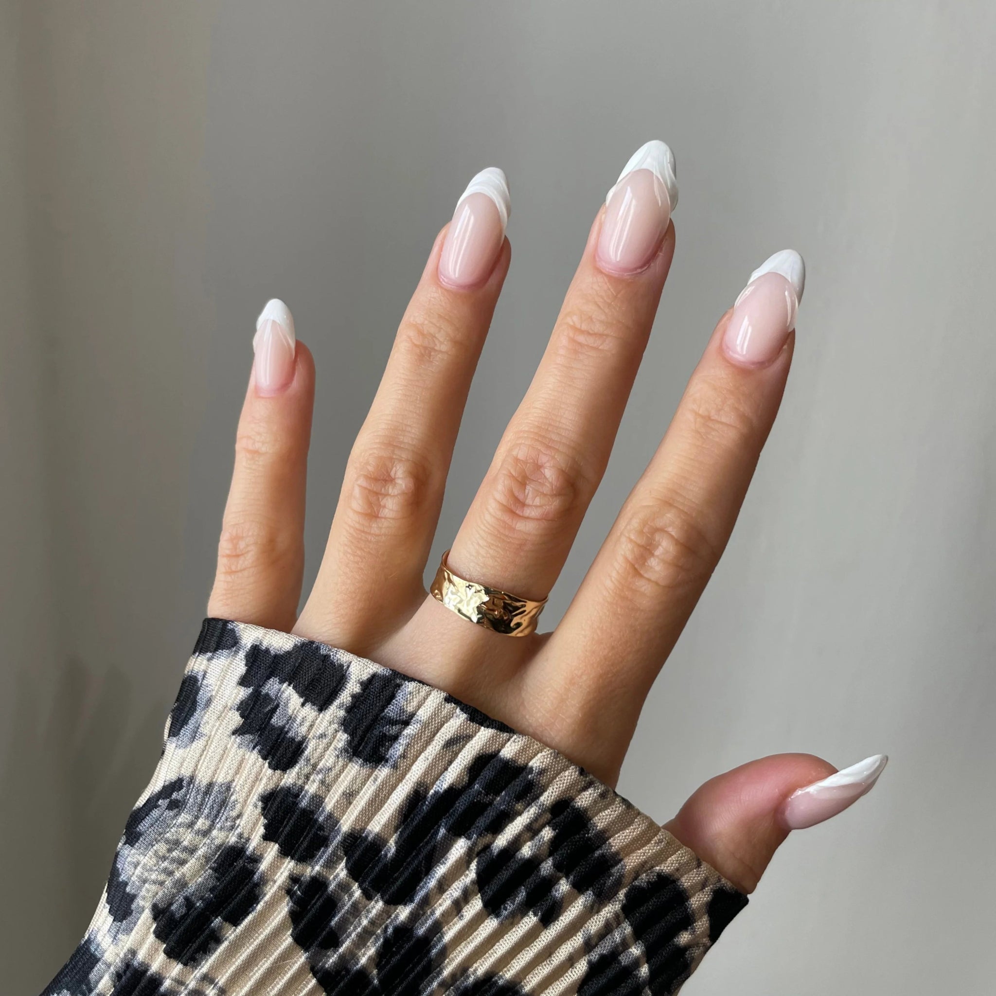 Bague large Svetlana portée en accumulation (stacking) avec d'autres bagues géométriques dorées.