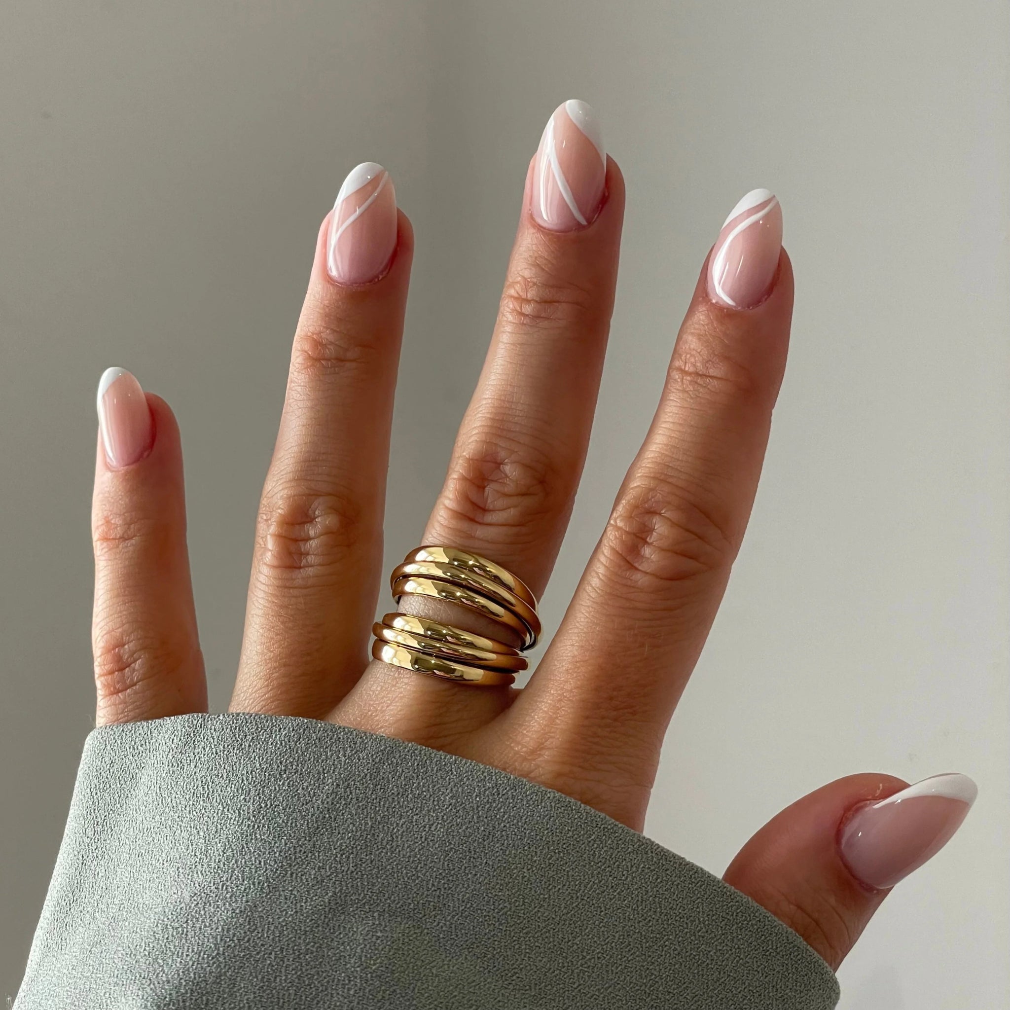 Bague Teresa portée en accumulation avec une bague bouclier filigrane sur une main avec manche grise.